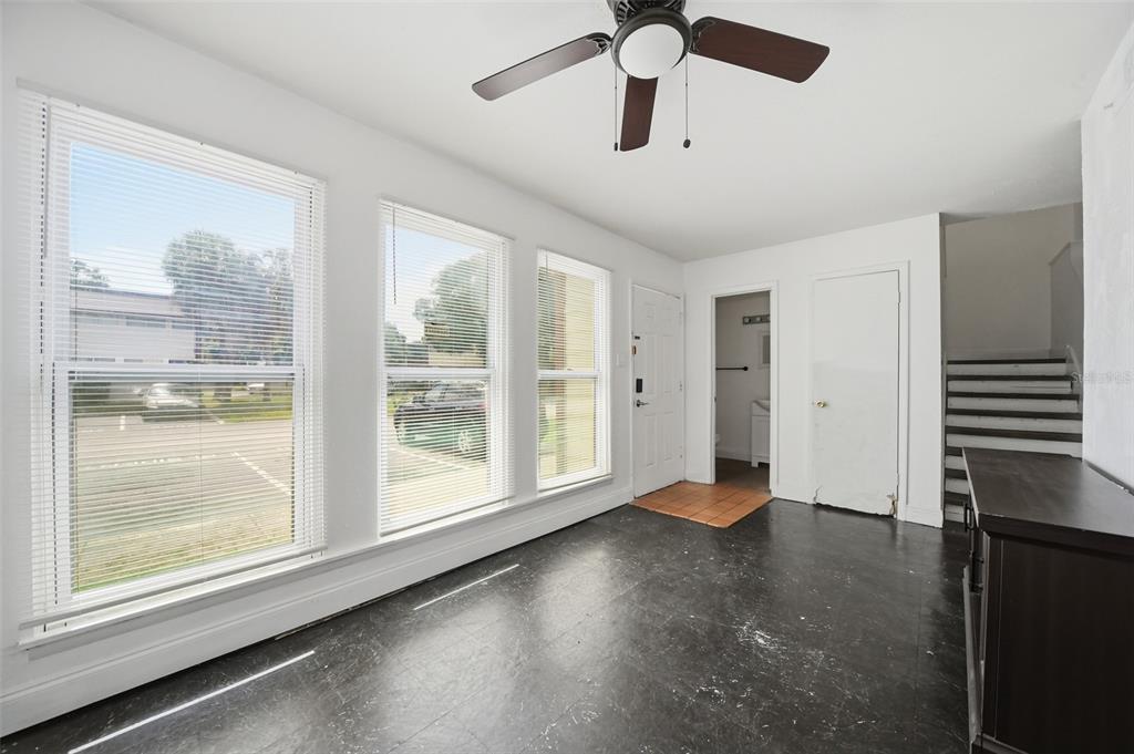 A room with black flooring, three large windows, a ceiling fan, and a staircase — 4001 DOLOMITE STREET UNIT B1, ORLANDO, FL