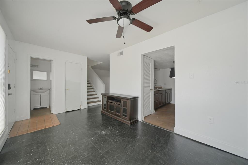 A living room with dark tile flooring, a ceiling fan, and a staircase — 4001 DOLOMITE STREET UNIT B1, ORLANDO, FL