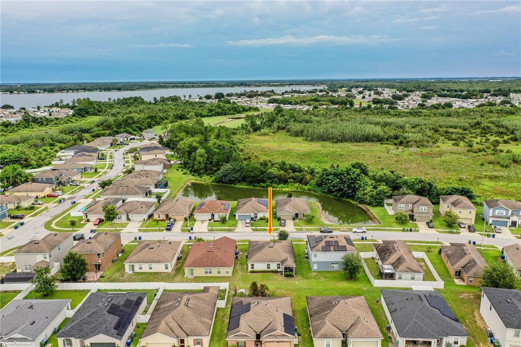 An aerial view shows a suburban neighborhood with houses, a small pond, and a large field — 256 OLEANDER STREET, WINTER HAVEN, FL