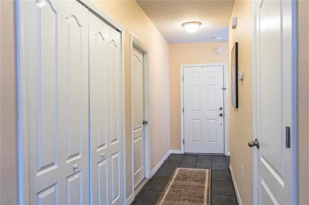 A hallway features tiled flooring, white doors, a closet, and a light fixture — 256 OLEANDER STREET, WINTER HAVEN, FL