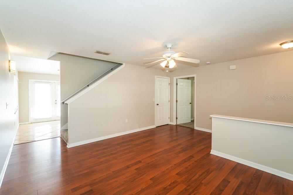 This living area features wood-look flooring, a ceiling fan, and a staircase with a railing — 10334 SUMMERVIEW CIRCLE, RIVERVIEW, FL
