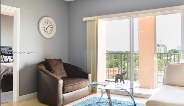 A living room features a brown armchair, a glass coffee table, and a balcony view — 2280 SW 32nd Ave # 613, Miami FL 33145, MIAMI, FL