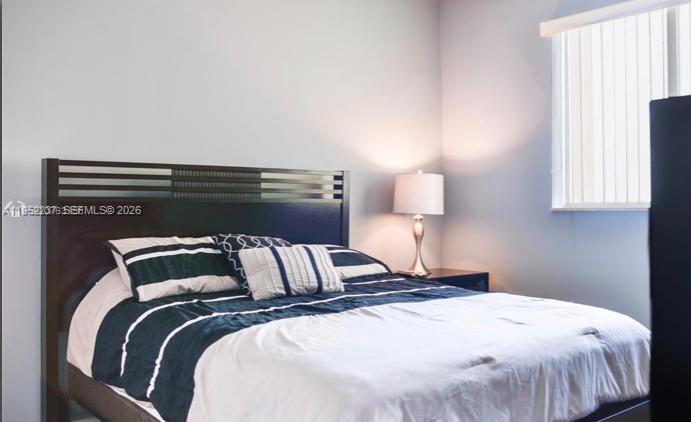 A bedroom features a dark wood bed frame with striped bedding and a bedside lamp — 2280 SW 32nd Ave # 613, Miami FL 33145, MIAMI, FL