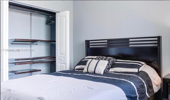 A bedroom features a dark wood headboard, a bed with striped bedding, and an open closet — 2280 SW 32nd Ave # 613, Miami FL 33145, MIAMI, FL