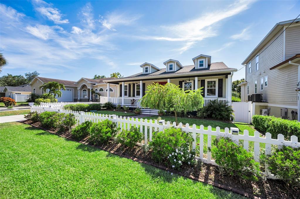 A single-story house with a front porch and three dormer windows behind a white fence — 3550 ROLANDO DRIVE, PALM HARBOR, FL