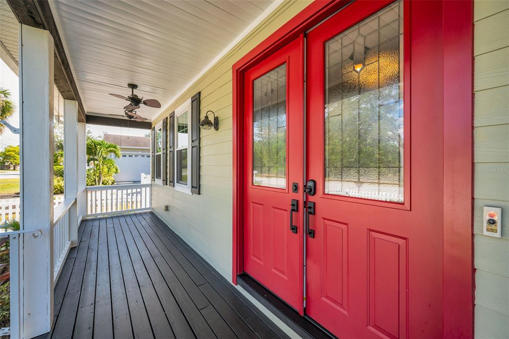 A covered porch features dark wooden flooring and a bright red double front door — 3550 ROLANDO DRIVE, PALM HARBOR, FL
