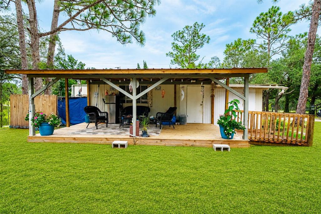 A wooden deck with a covered patio area sits in front of a mobile home — 5108 W FIELD STREET, HOMOSASSA, FL