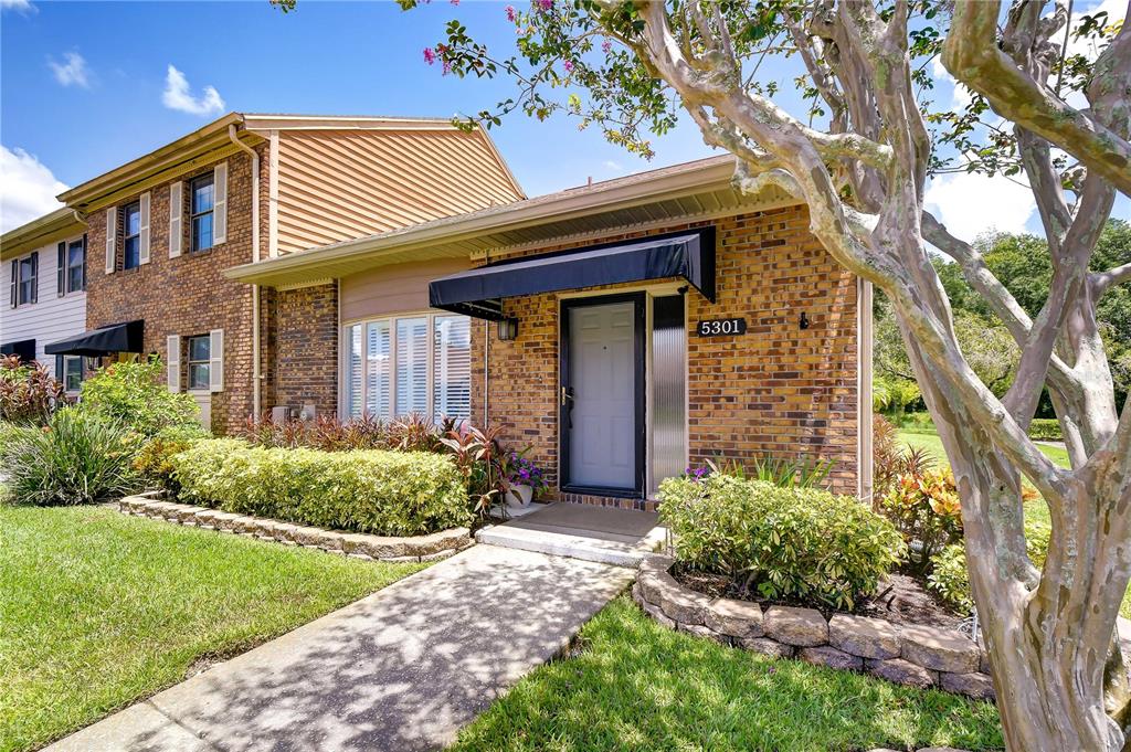 A brick townhouse exterior features a front walkway, landscaping, and a black metal door awning — 5301 BRADBURY COURT, TAMPA, FL