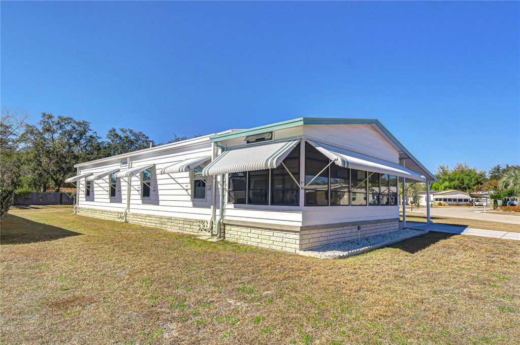 A white mobile home with a screened-in porch and a stone-patterned base — 4843 BLANCO DRIVE, ZEPHYRHILLS, FL