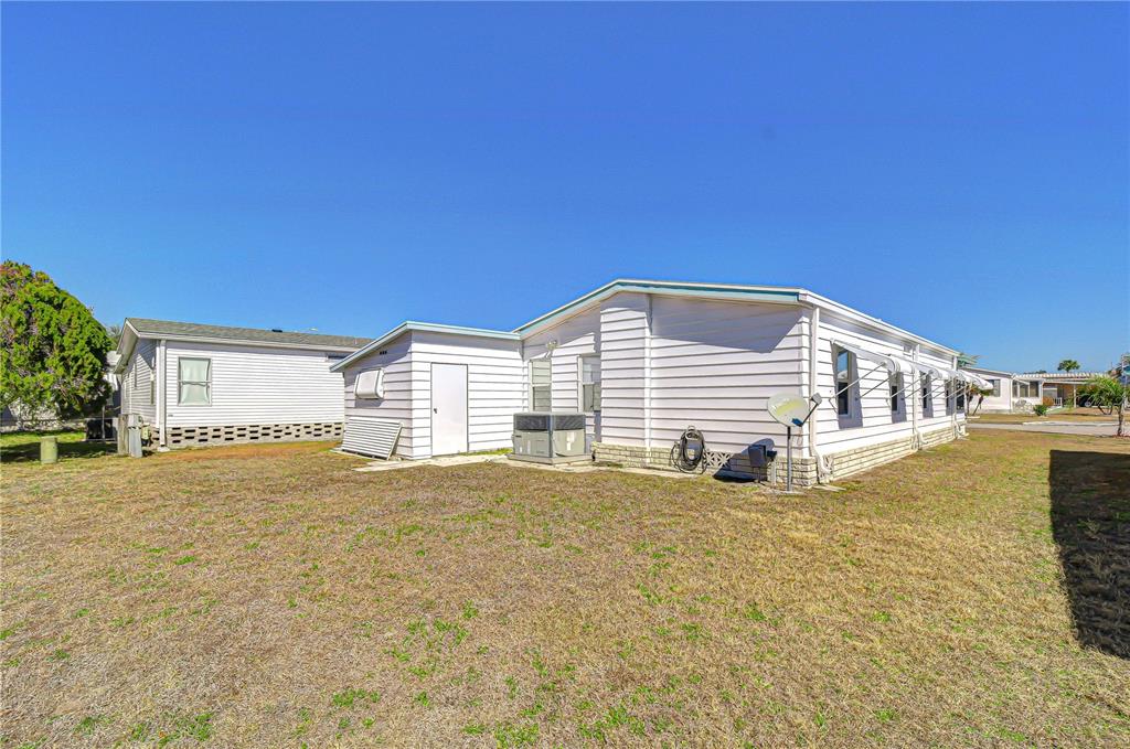 The exterior of a white mobile home features horizontal siding and a grassy yard — 4843 BLANCO DRIVE, ZEPHYRHILLS, FL