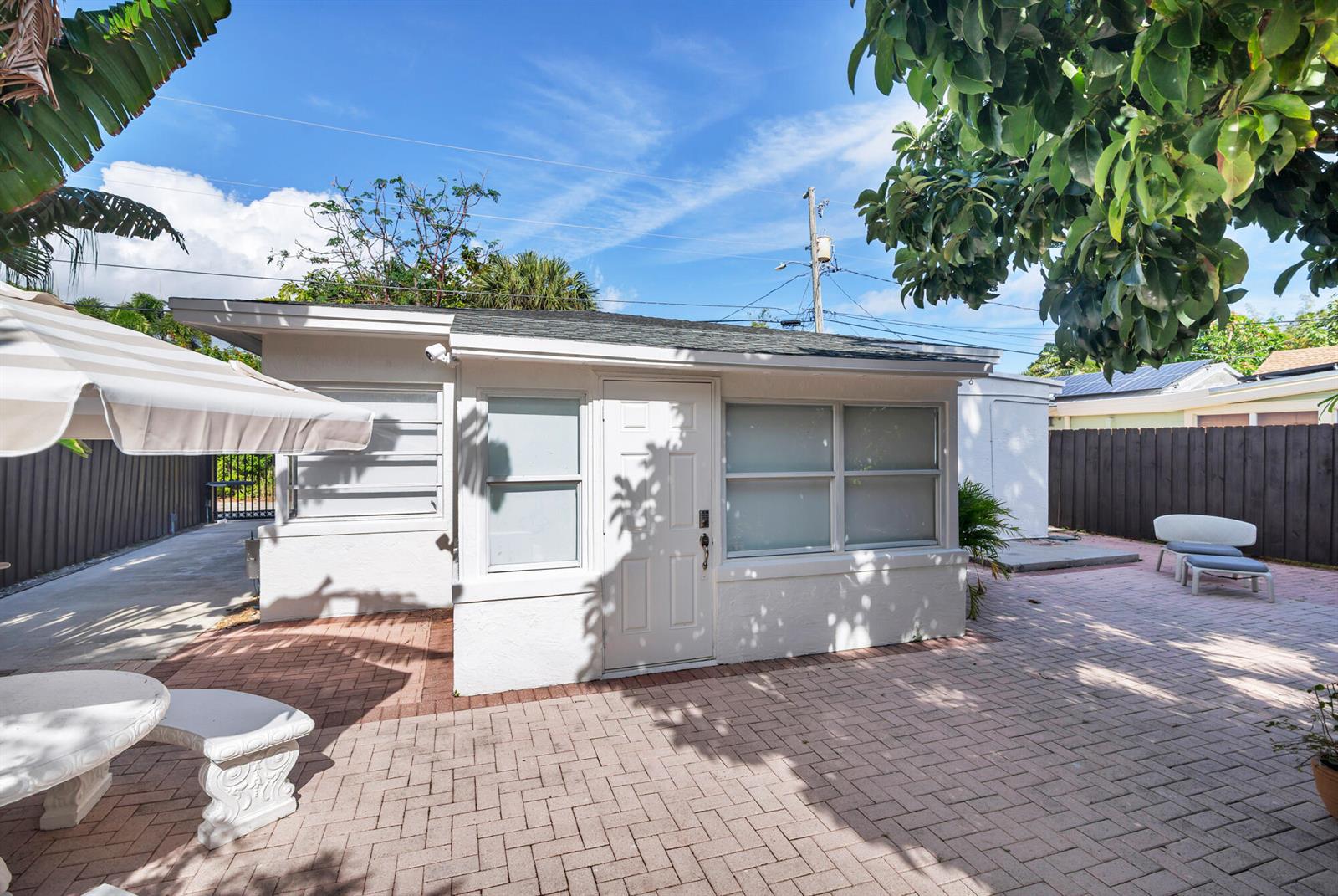 A small white detached building sits on a brick patio under a bright blue sky — 439 28th Street, West Palm Beach FL 33407, WEST PALM BEACH, FL