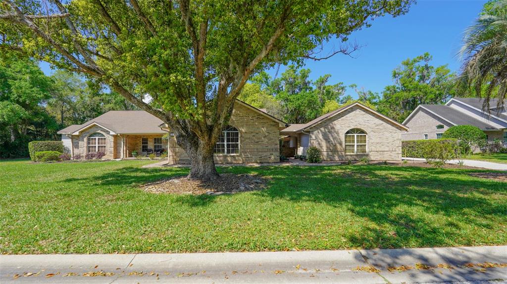 A single-story brick house with a large tree in the front yard — 204 BRYNWOOD LANE, SANFORD, FL