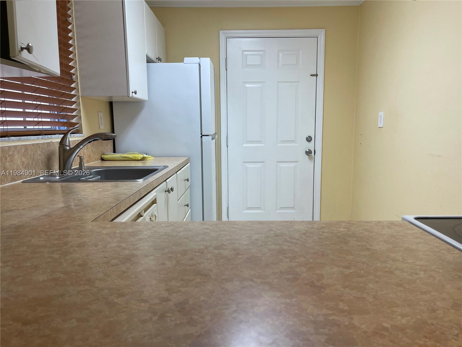 A kitchen features white cabinets, a stainless steel sink, a refrigerator, and tan countertops — 8600 SW 109th Ave # 220, Miami FL 33173, MIAMI, FL