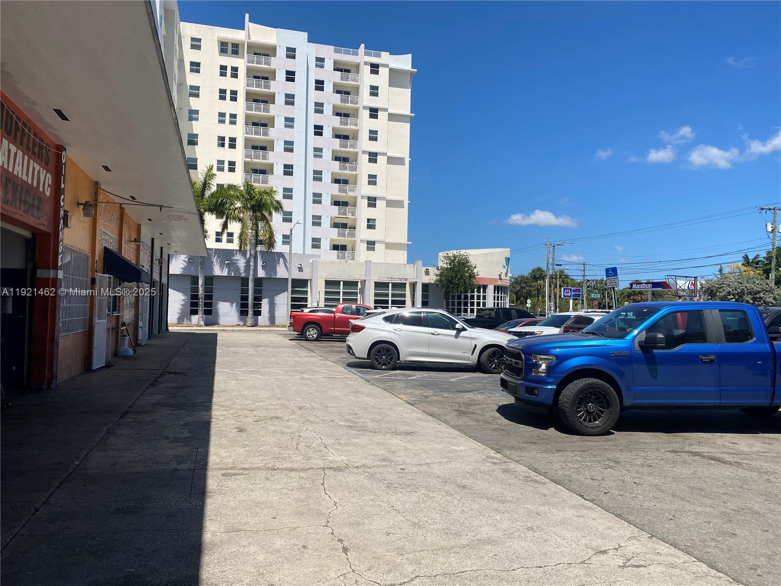 A parking lot sits in front of a commercial building and a tall apartment complex — 2300 NW 17th St, Miami FL 33142, MIAMI, FL