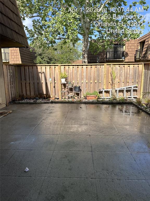 A concrete patio enclosed by a wooden privacy fence with potted plants and a ladder — 5344 BAMBOO COURT, ORLANDO, FL