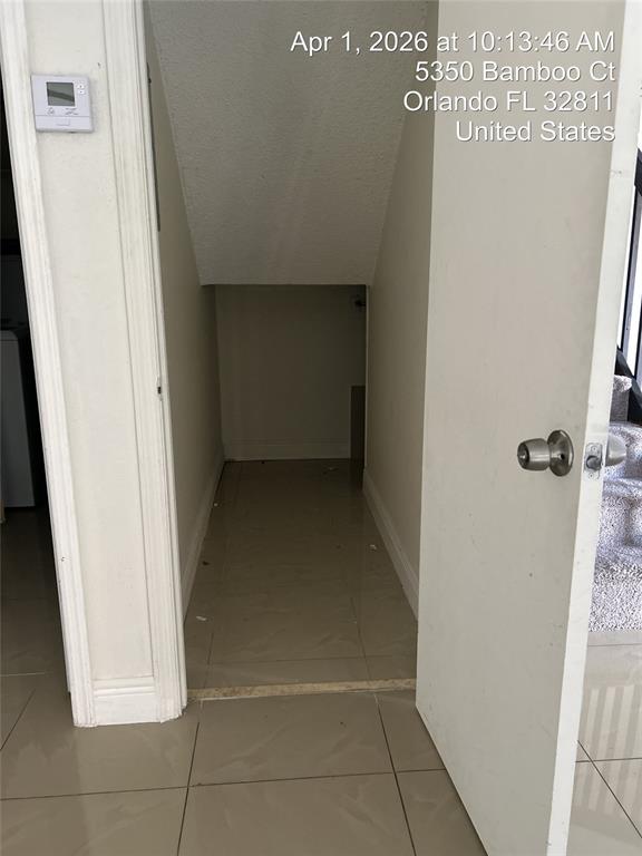 An open door reveals a small, empty storage closet with tile flooring under a staircase — 5344 BAMBOO COURT, ORLANDO, FL