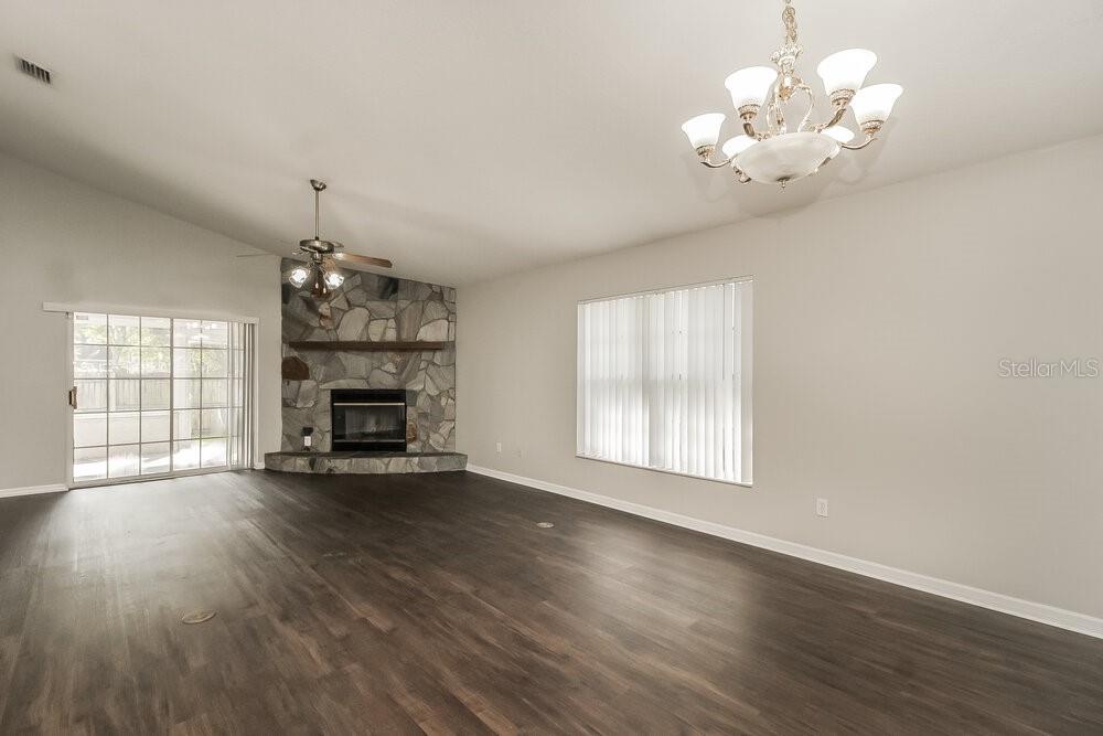 A living room features dark wood-look flooring, a stone fireplace, and a ceiling fan — 1060 COVINGTON STREET, OVIEDO, FL