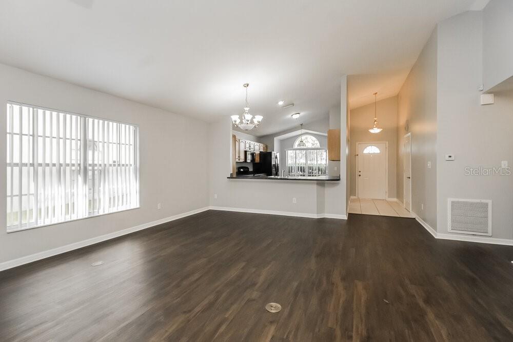 An open-concept living area features dark wood-look flooring, light gray walls, and a kitchen pass-through — 1060 COVINGTON STREET, OVIEDO, FL