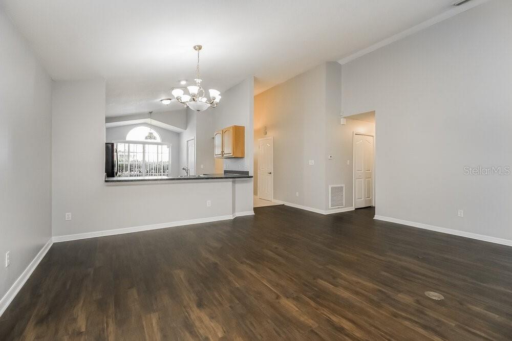 An open-concept living area features dark wood-look flooring, light gray walls, and a kitchen pass-through — 1060 COVINGTON STREET, OVIEDO, FL