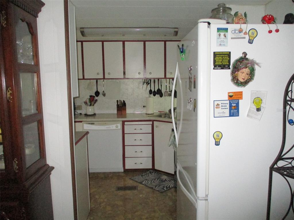 A kitchen features white cabinets with red trim, a white refrigerator, and a dishwasher — 38513 WILLOUGHBY DRIVE, ZEPHYRHILLS, FL