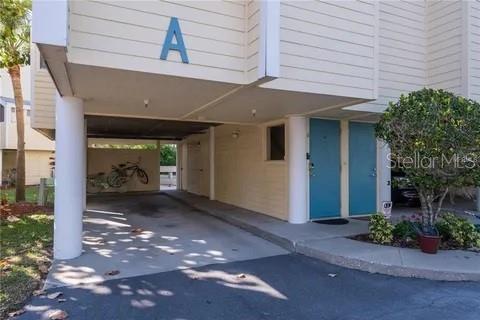 The exterior of a building features a covered parking area and two blue doors — 1500 SUNSET ROAD UNIT A6, TARPON SPRINGS, FL