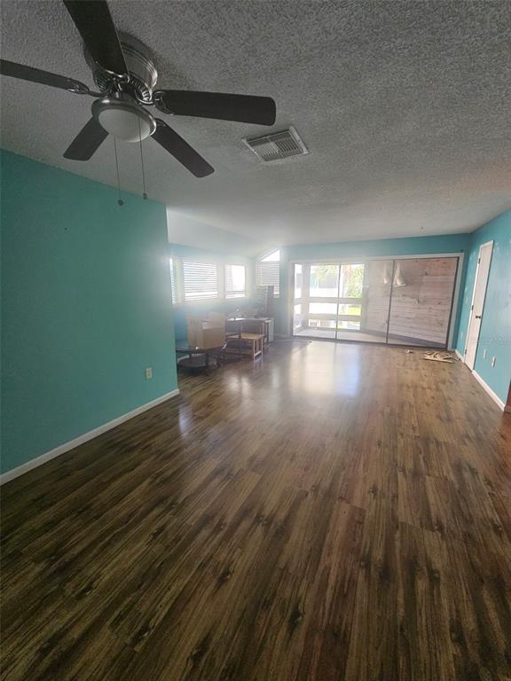 A living room features wood-look flooring, teal walls, a ceiling fan, and sliding glass doors — 1500 SUNSET ROAD UNIT A6, TARPON SPRINGS, FL