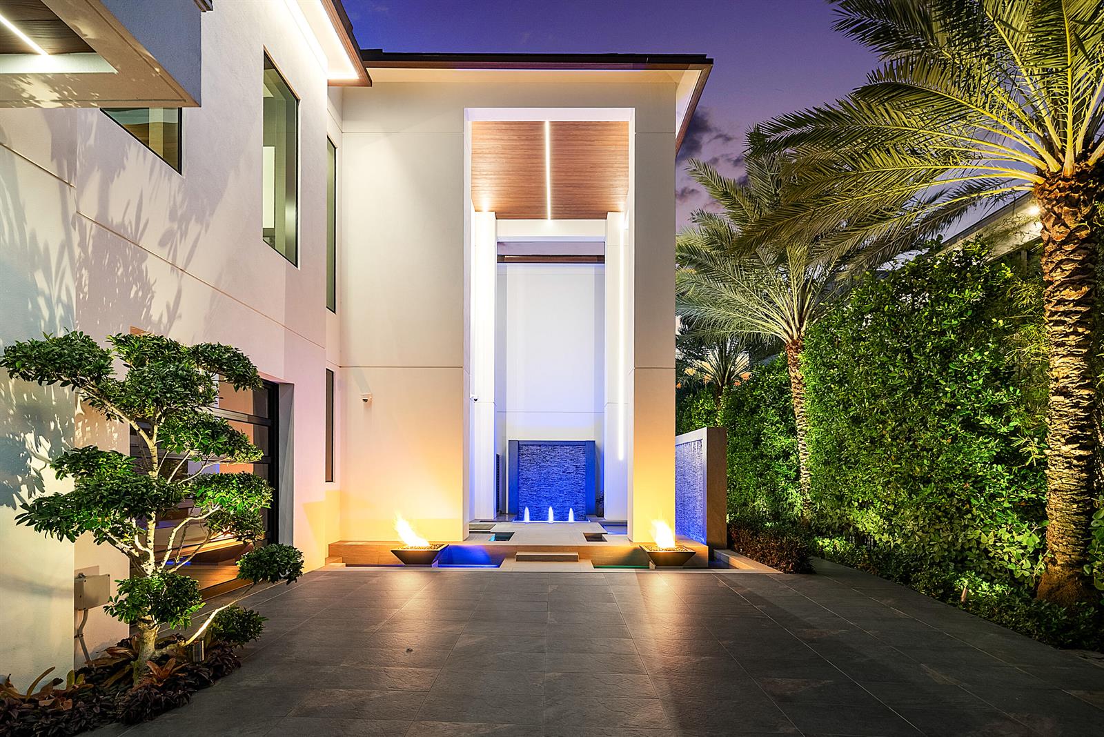 A modern home exterior features a tall entryway with a blue water feature and fire bowls — 2934 NE 8th Avenue, Boca Raton FL 33431, BOCA RATON, FL