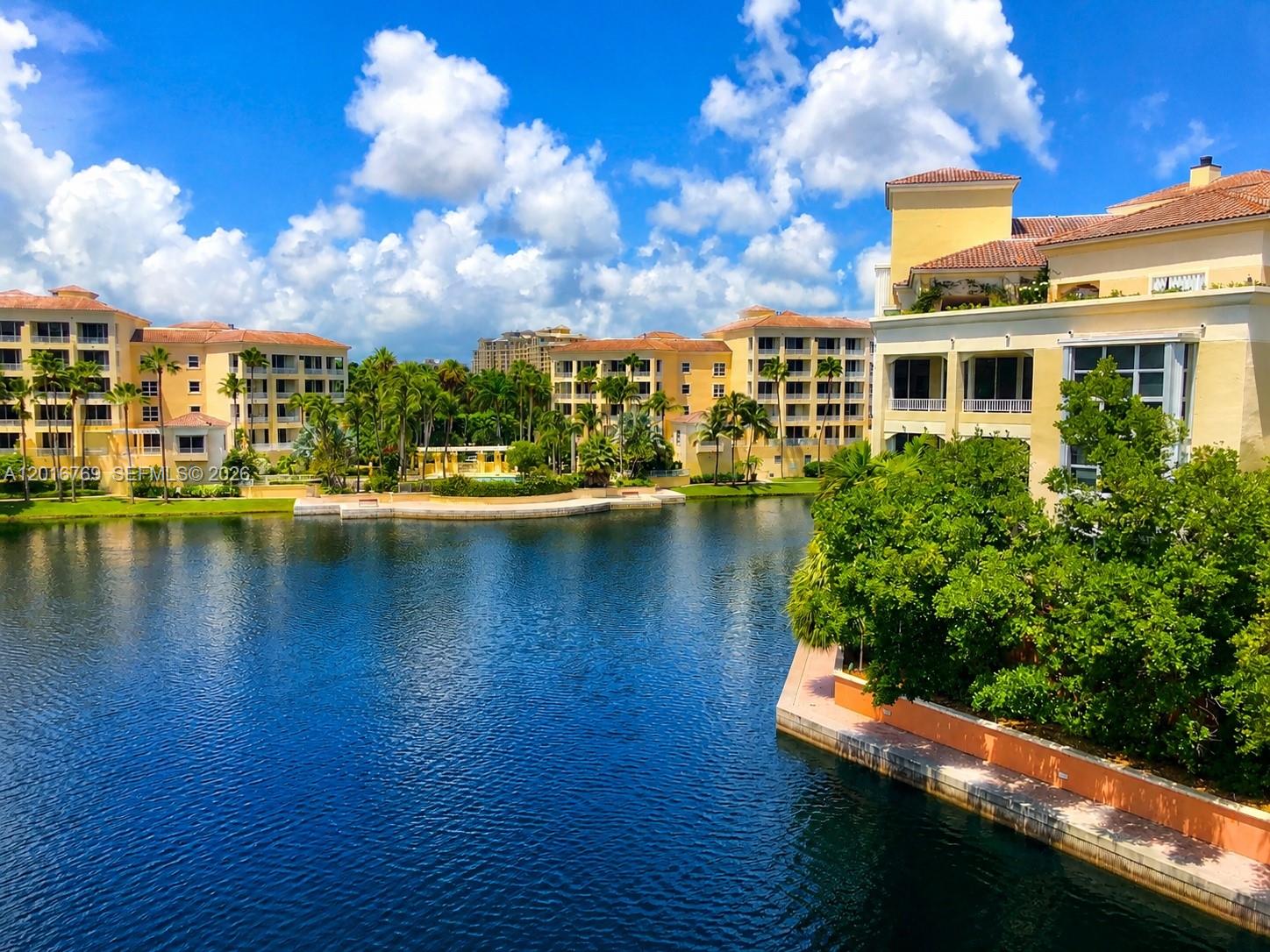 A bright living room features white sofas, a leather ottoman, and a large glass balcony — 737 Crandon Blvd # 402, Key Biscayne FL 33149, KEY BISCAYNE, FL