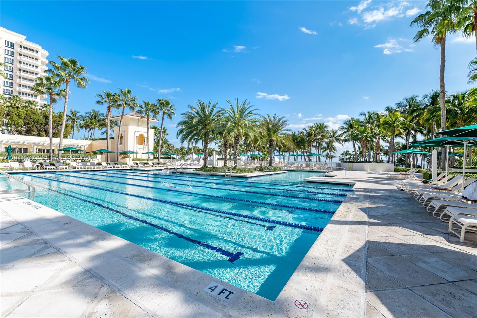 A living room features white sofas, a leather ottoman, and large glass doors to a balcony — 737 Crandon Blvd # 402, Key Biscayne FL 33149, KEY BISCAYNE, FL
