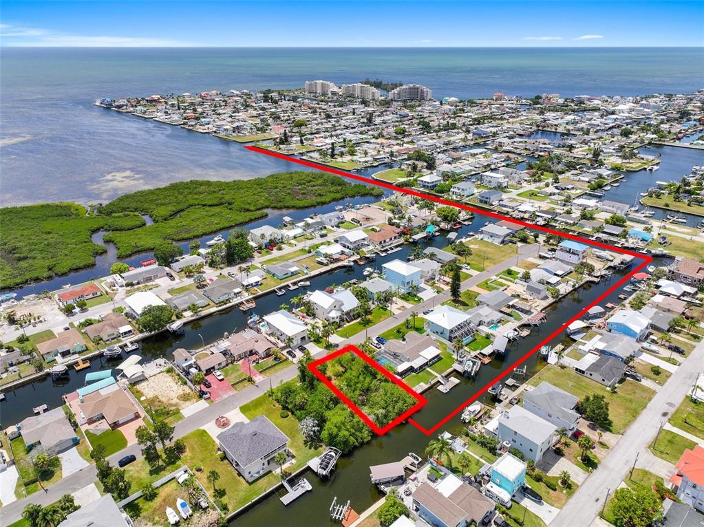 This aerial view shows a vacant waterfront lot outlined in red within a residential canal community — 13330 SUNFISH DRIVE, HUDSON, FL