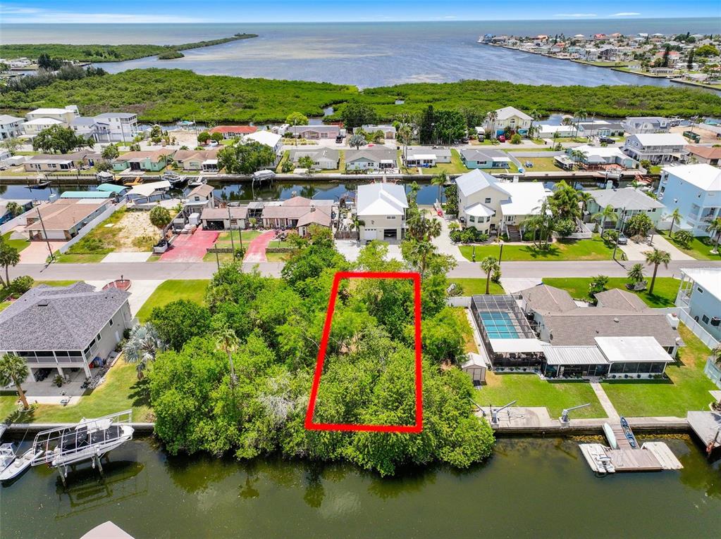 An aerial view shows a vacant, tree-covered waterfront lot outlined in red — 13330 SUNFISH DRIVE, HUDSON, FL