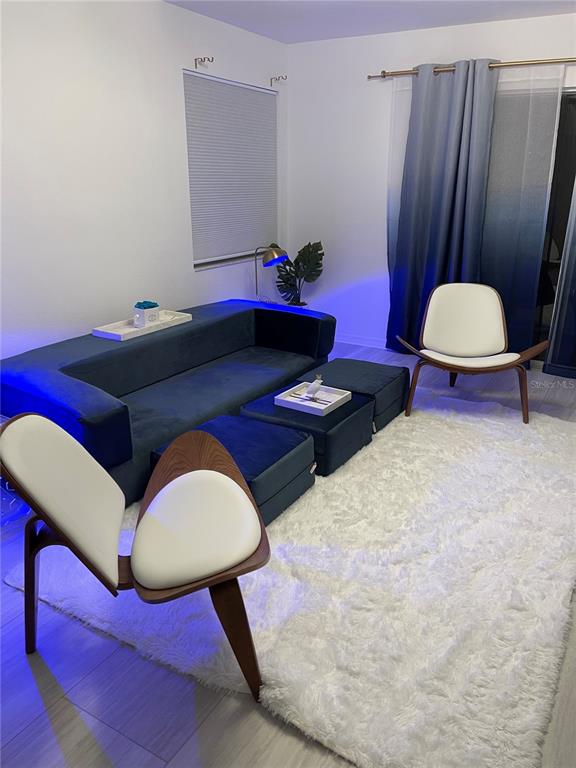 A living room features a blue velvet sofa, two matching ottomans, and two modern chairs — 6826 STONES THROW CIRCLE N UNIT 11108, ST PETERSBURG, FL