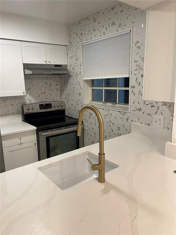 A kitchen features white cabinets, a quartz countertop, a gold faucet, and patterned wallpaper — 6826 STONES THROW CIRCLE N UNIT 11108, ST PETERSBURG, FL
