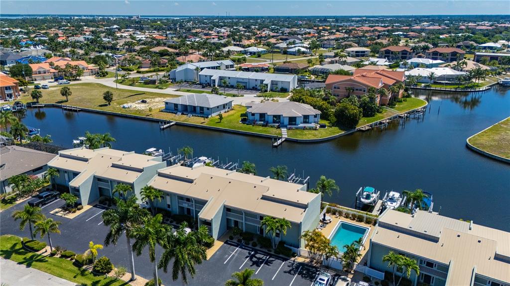 An aerial view shows waterfront townhomes with boat slips, a swimming pool, and parking lots — 1400 MINEO DRIVE UNIT 12D, PUNTA GORDA, FL