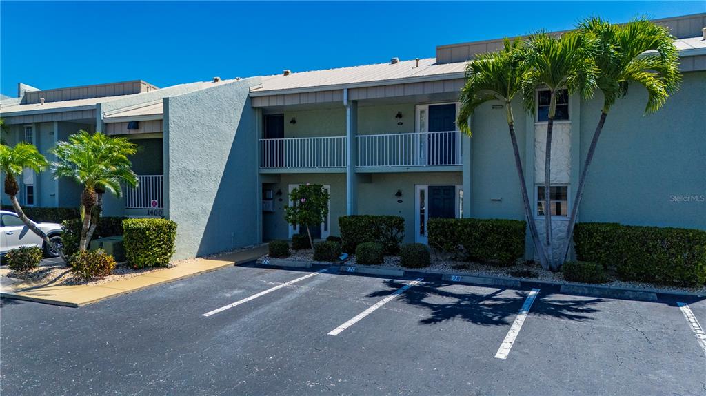 A two-story apartment building with a parking lot and palm trees in front — 1400 MINEO DRIVE UNIT 12D, PUNTA GORDA, FL
