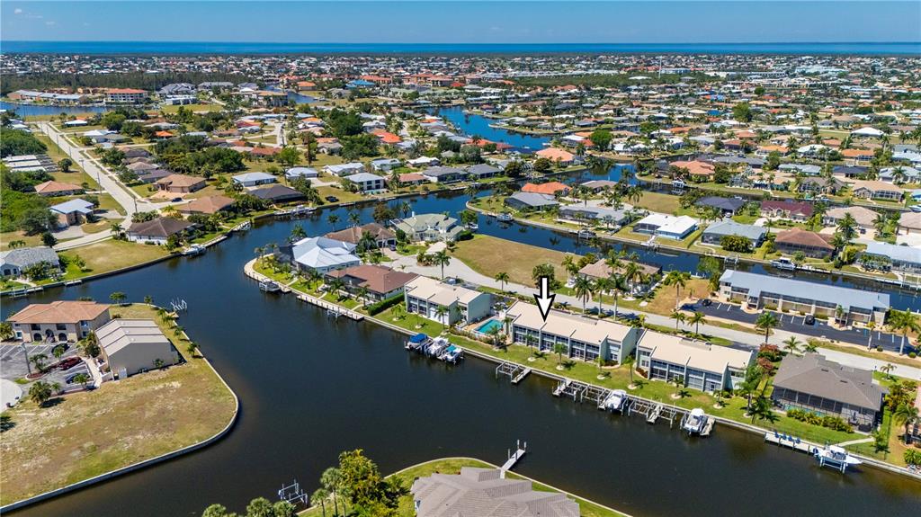 An aerial view shows a multi-unit waterfront residential building with boat docks and canals — 1400 MINEO DRIVE UNIT 12D, PUNTA GORDA, FL
