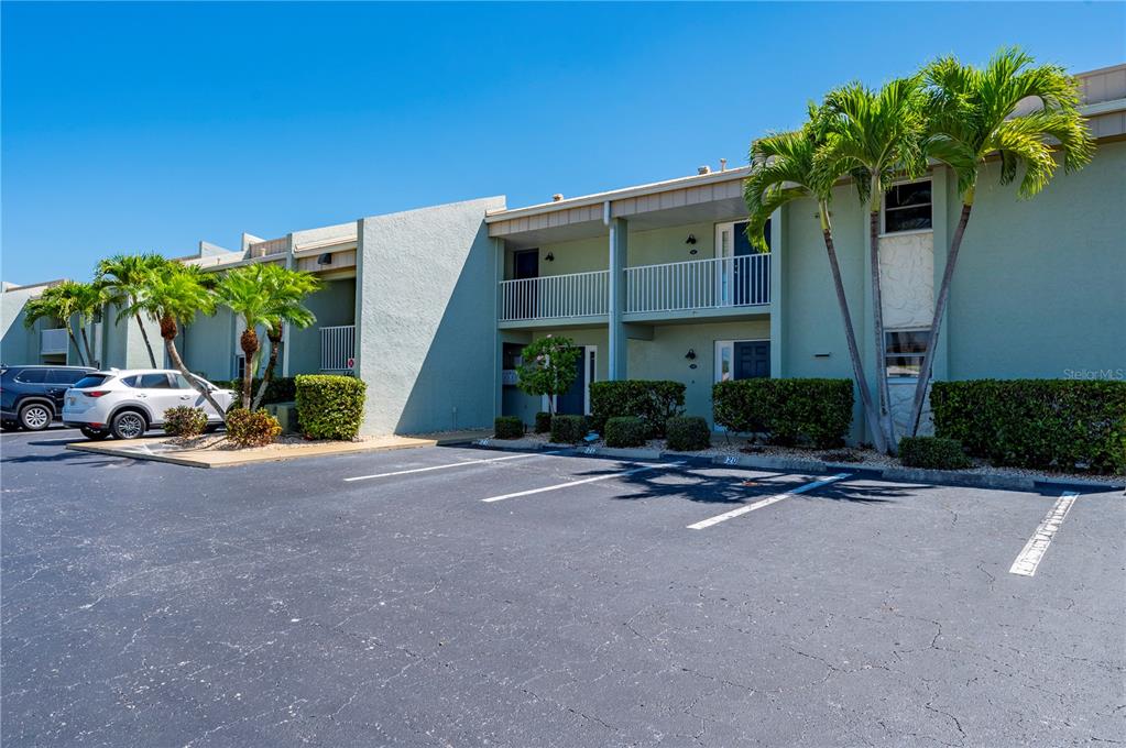 A two-story apartment building with a parking lot and palm trees in front — 1400 MINEO DRIVE UNIT 12D, PUNTA GORDA, FL