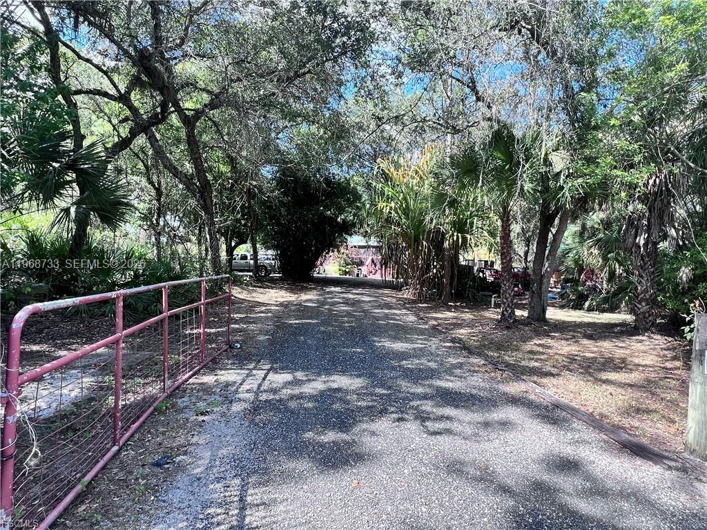 A gravel driveway leads through a wooded area toward a house behind a metal gate — 680 S Arboleda, Clewiston FL 33440, CLEWISTON, FL