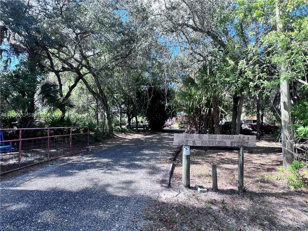 A gravel driveway leads into a wooded area with a wooden sign marking the road — 680 S Arboleda, Clewiston FL 33440, CLEWISTON, FL