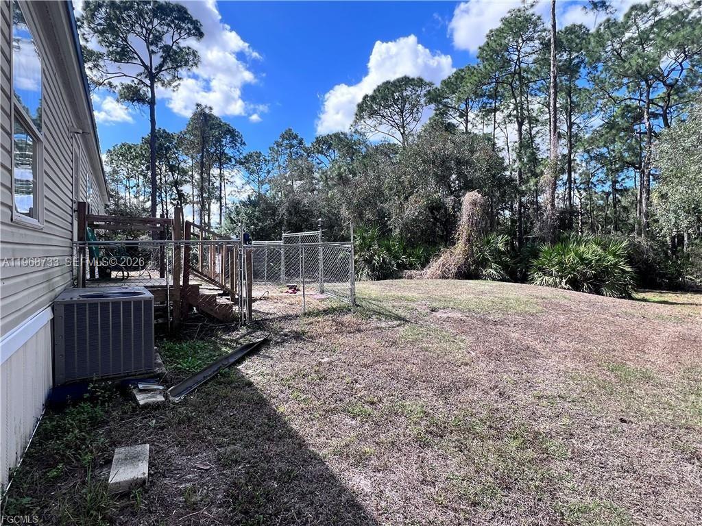 A side view of a house exterior featuring a wooden deck, chain-link fence, and yard — 680 S Arboleda, Clewiston FL 33440, CLEWISTON, FL