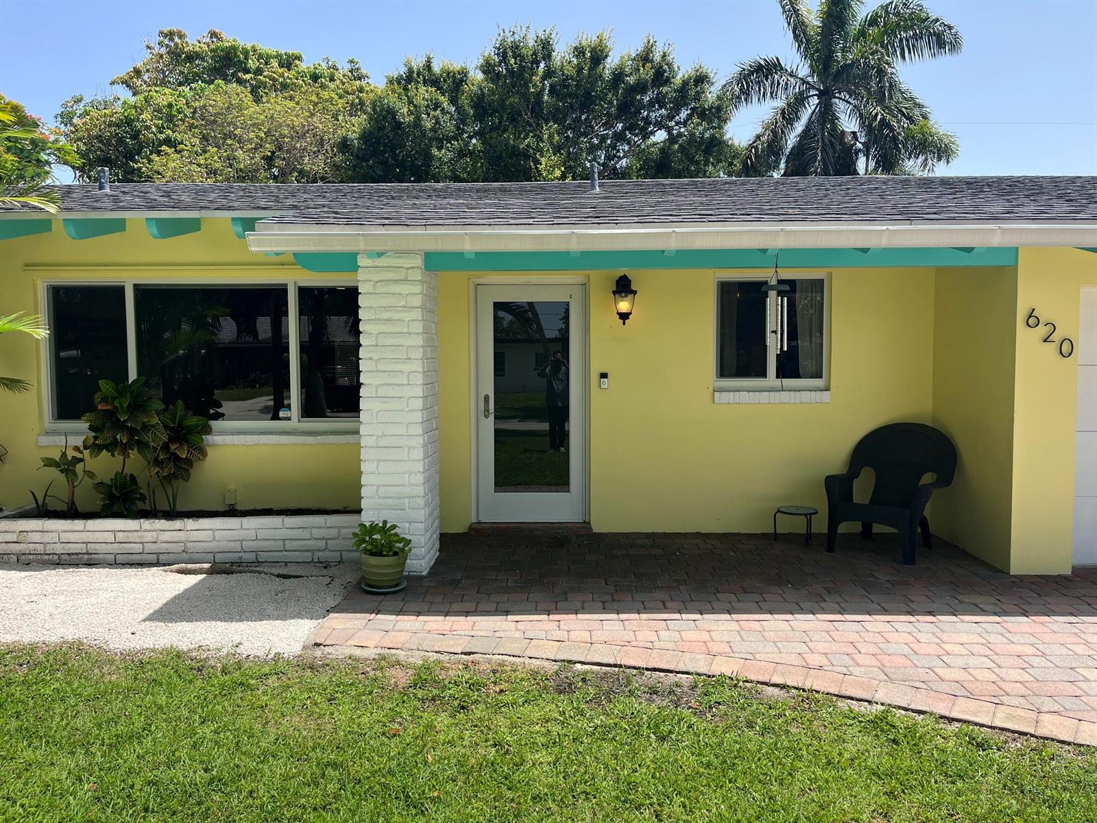 A yellow house exterior features a white brick pillar, turquoise trim, and a brick patio — 620 NE 9th Avenue, Boynton Beach FL 33435, BOYNTON BEACH, FL