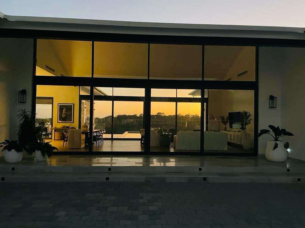 A modern home exterior features large glass sliding doors and a patio at sunset — Las Lagartijas San Carlos, Cocle, FL