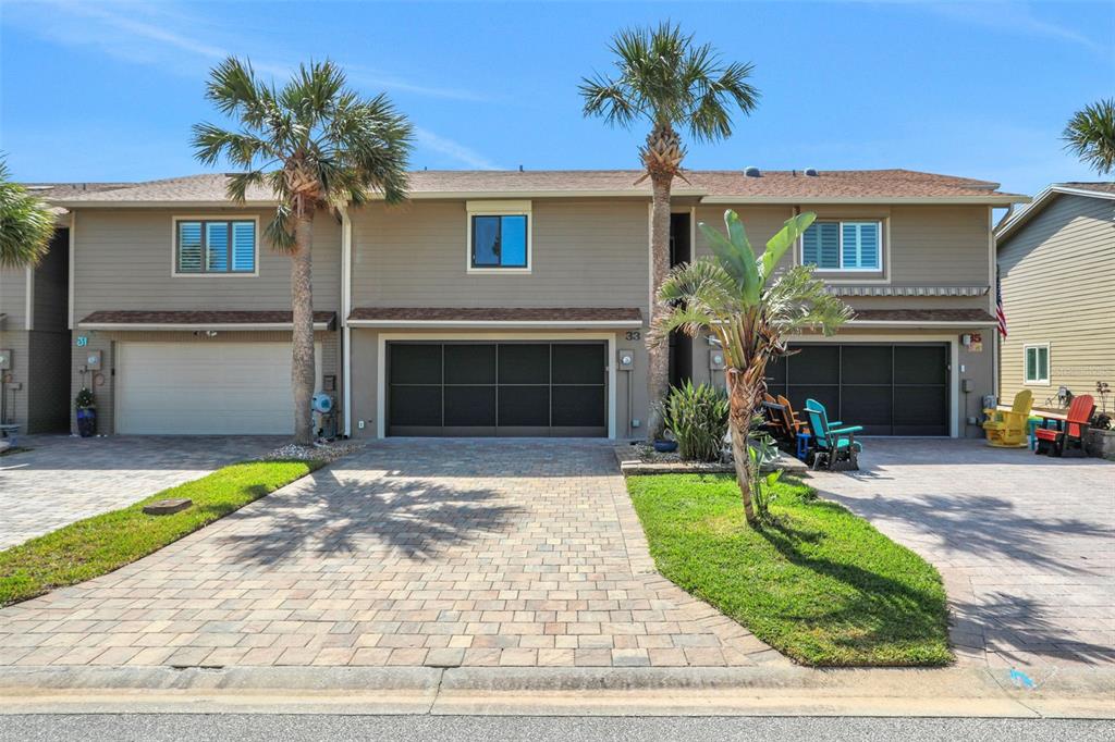 A two-story townhouse exterior features a paved driveway, garage doors, and two palm trees — 33 SEA HAVEN DRIVE, PONCE INLET, FL