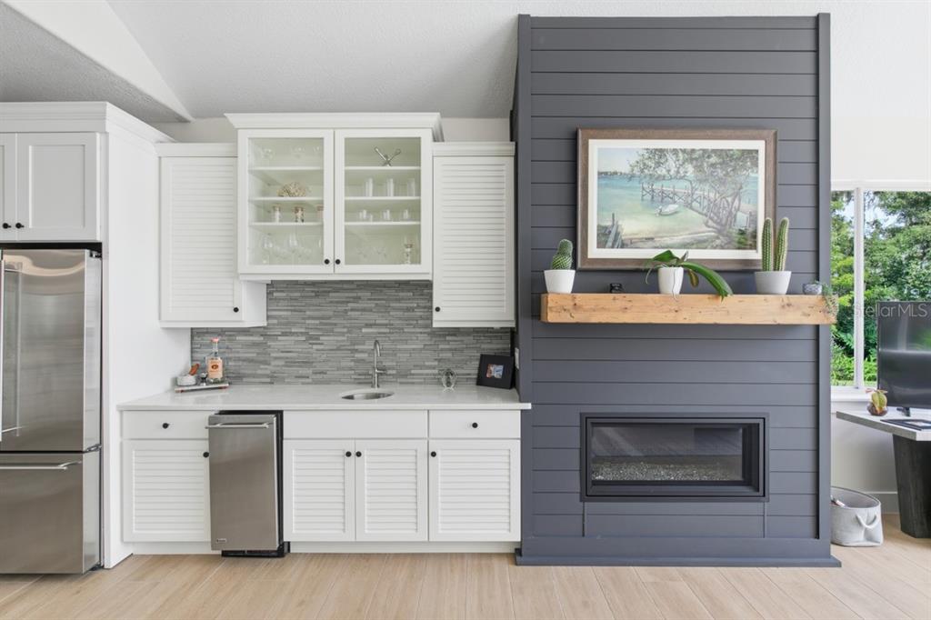 A wet bar with white cabinetry and a gray shiplap fireplace wall with a wood mantel — 4733 CHULUOTA ROAD, ORLANDO, FL