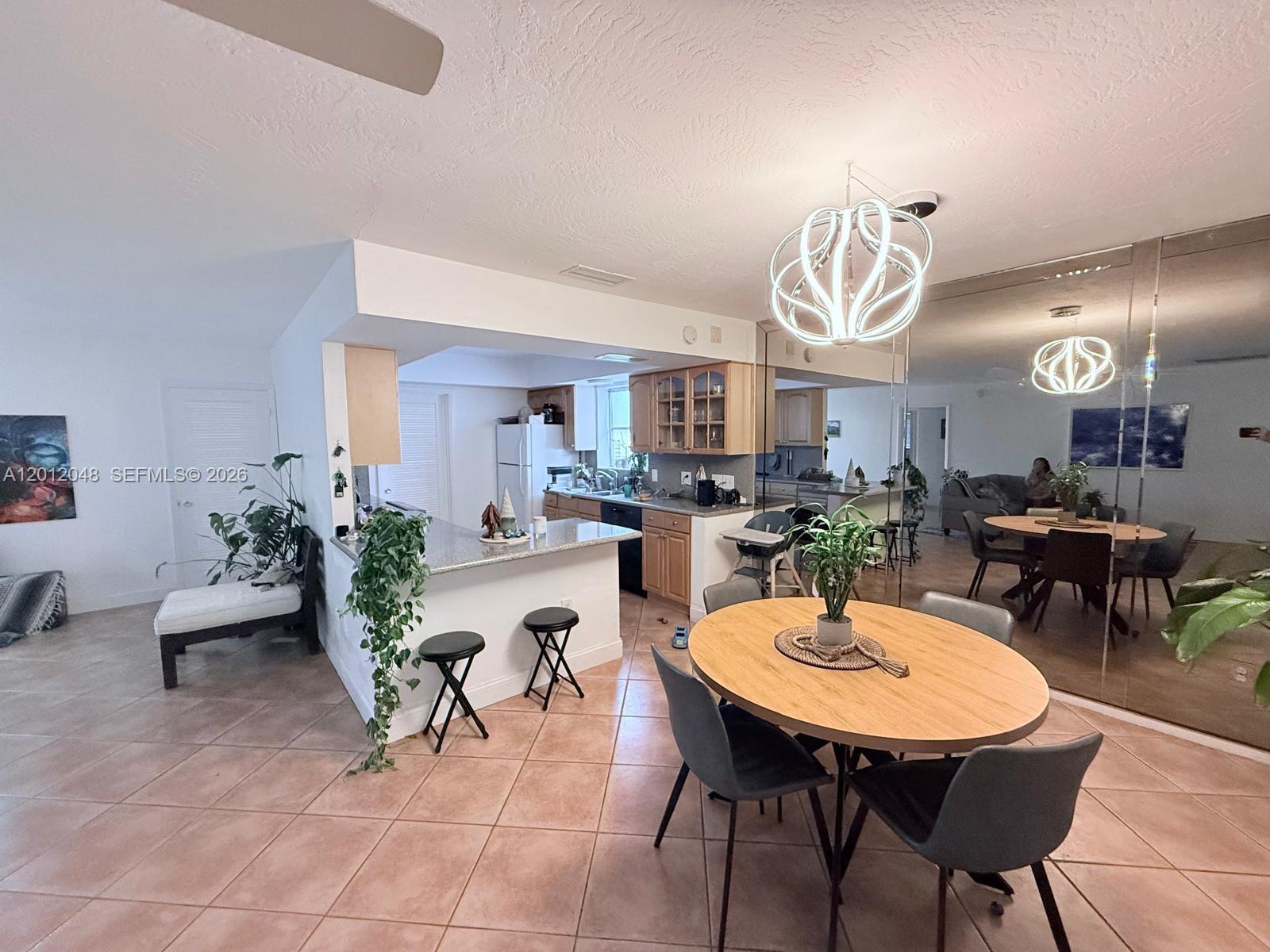 A kitchen with light wood cabinets and a breakfast bar opens to a dining area — 9356 Byron Ave, Surfside FL 33154, SURFSIDE, FL