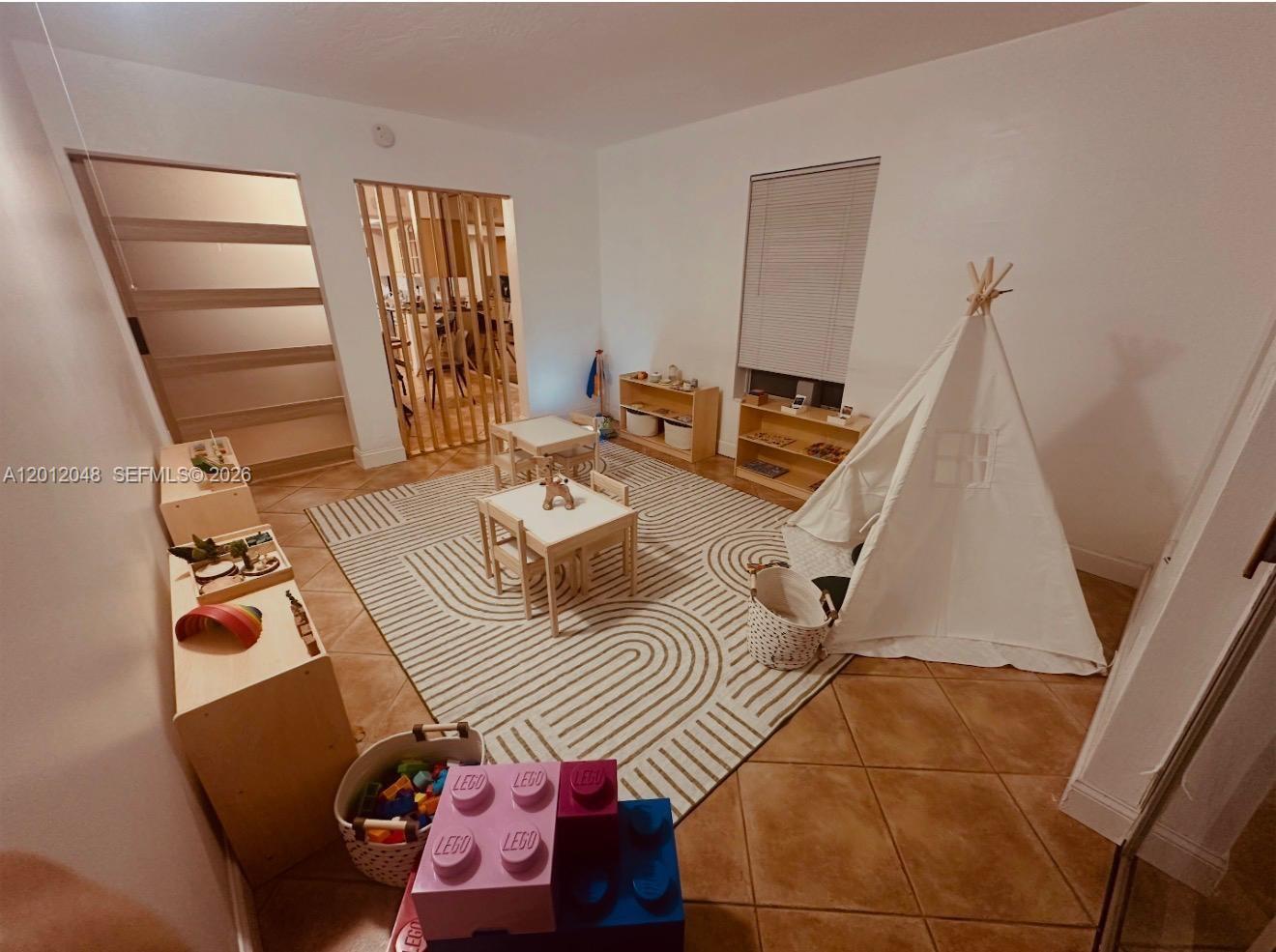 A children's playroom features a teepee, small tables, toy storage shelves, and a patterned rug — 9356 Byron Ave, Surfside FL 33154, SURFSIDE, FL