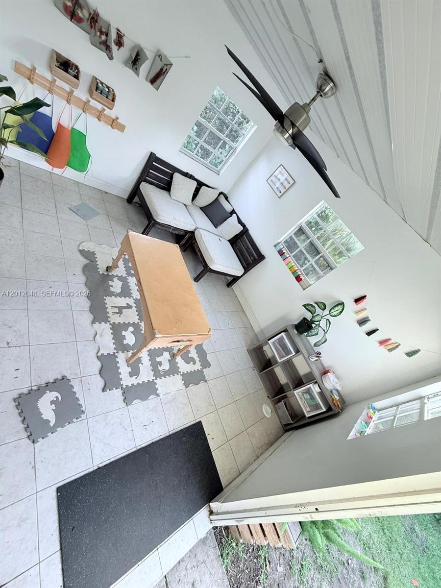 A sunroom features tile flooring, a ceiling fan, a wooden bench, and a play area — 9356 Byron Ave, Surfside FL 33154, SURFSIDE, FL