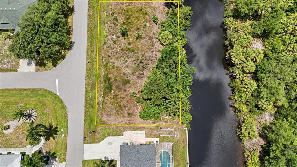 An aerial view shows a vacant, rectangular lot bordered by a road and a canal — 3367 DESOTO DRIVE, PUNTA GORDA, FL