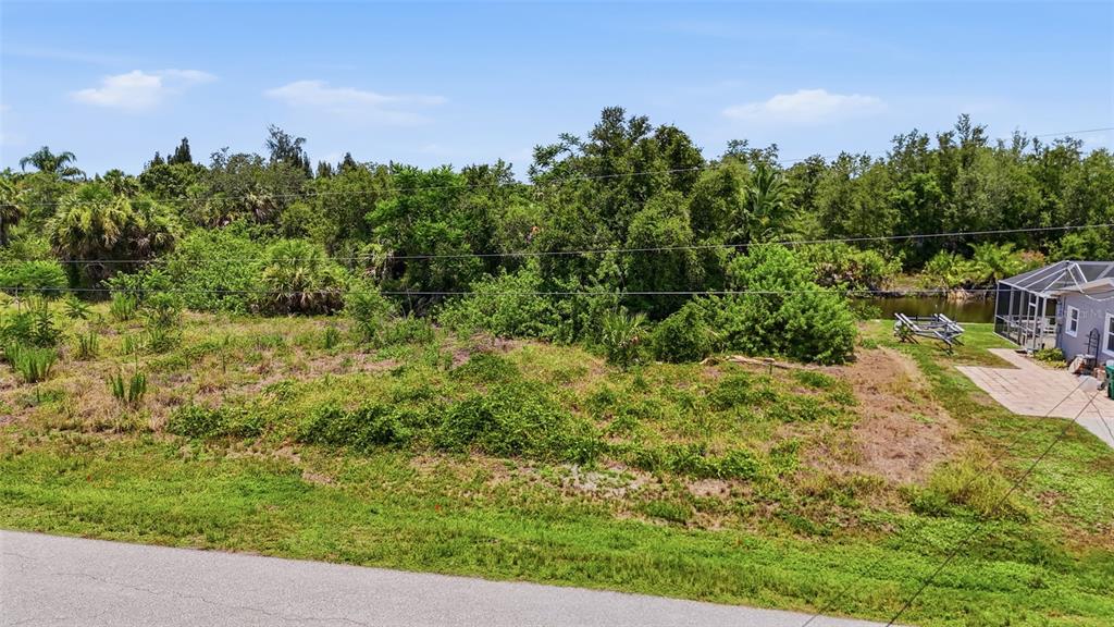 An elevated view of a vacant, overgrown lot next to a house with a screened patio — 3367 DESOTO DRIVE, PUNTA GORDA, FL