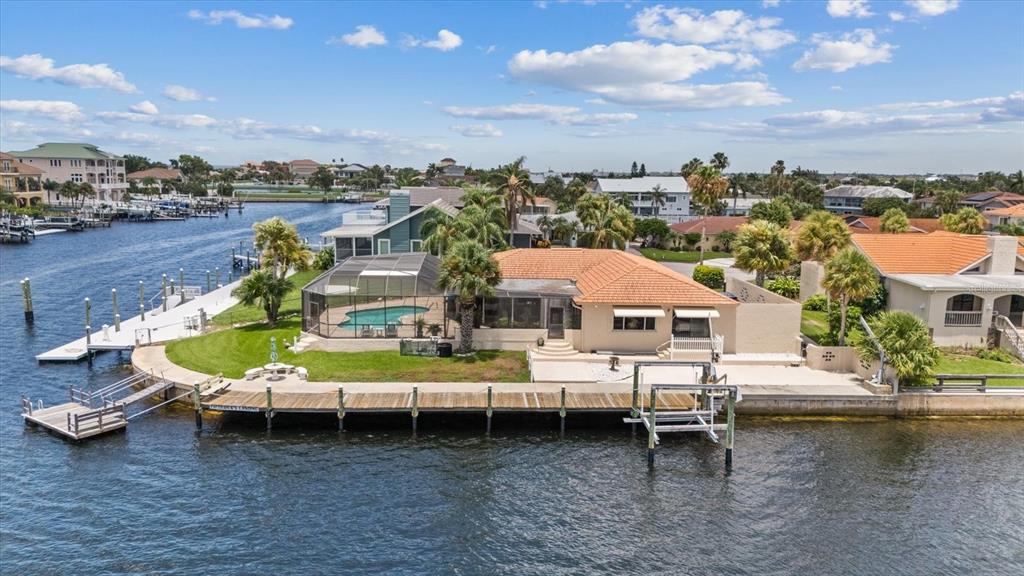An aerial view of a waterfront house with a pool, screened lanai, and wooden dock — 3154 TRIDENT TERRACE, NEW PORT RICHEY, FL